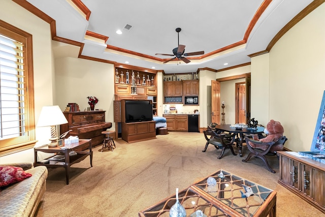 carpeted living room featuring a raised ceiling, ornamental molding, and ceiling fan