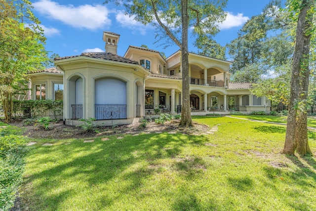 back of property with a balcony and a yard