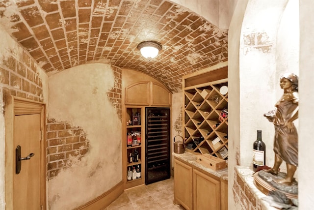 wine area featuring lofted ceiling, brick ceiling, and beverage cooler