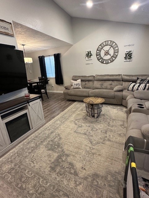 living room with wood-type flooring, a textured ceiling, and vaulted ceiling