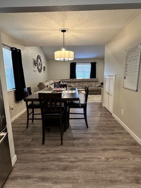 dining space featuring dark wood-type flooring and a textured ceiling