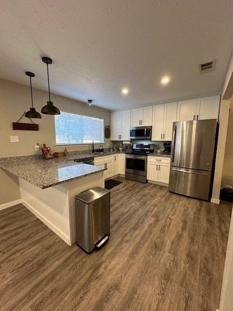 kitchen with stainless steel appliances, kitchen peninsula, dark hardwood / wood-style floors, hanging light fixtures, and white cabinets