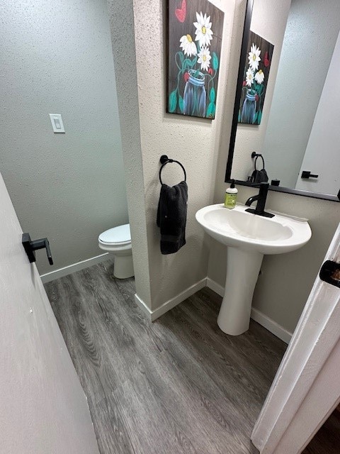 bathroom featuring toilet and wood-type flooring