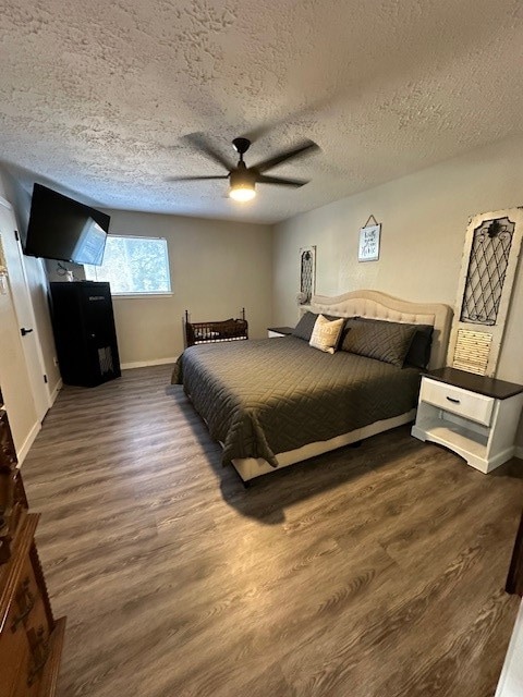 bedroom with dark wood-type flooring, a textured ceiling, and ceiling fan