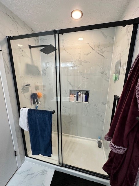 bathroom with a textured ceiling and a shower with door