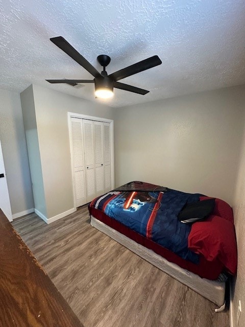 bedroom with a closet, hardwood / wood-style floors, ceiling fan, and a textured ceiling