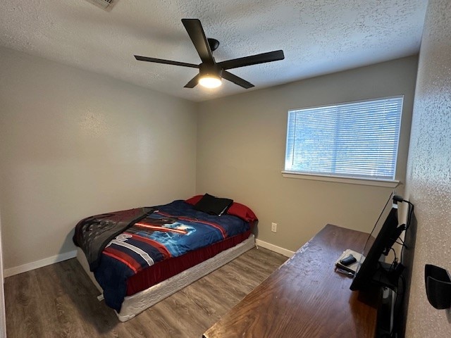 bedroom featuring dark wood-type flooring, ceiling fan, and a textured ceiling