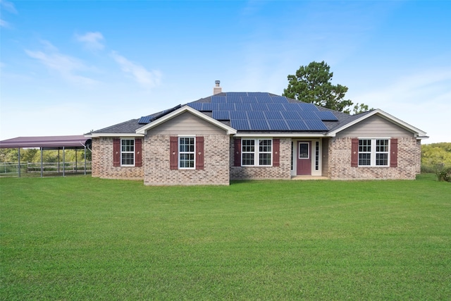 rear view of house featuring a lawn, a carport, and solar panels