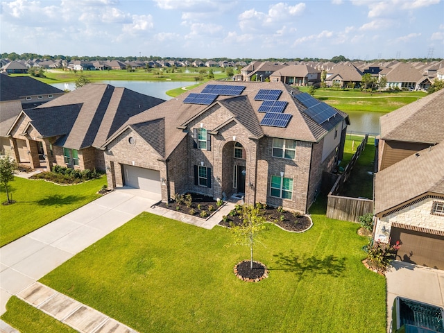 view of front of house featuring a garage, solar panels, a front lawn, and a water view