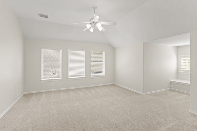 carpeted empty room featuring ceiling fan, plenty of natural light, and vaulted ceiling