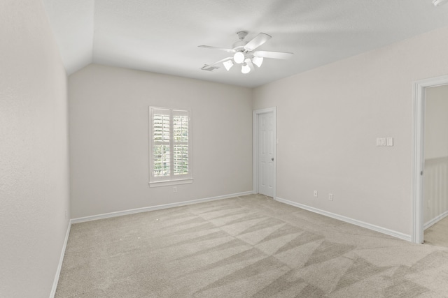 carpeted spare room featuring vaulted ceiling and ceiling fan