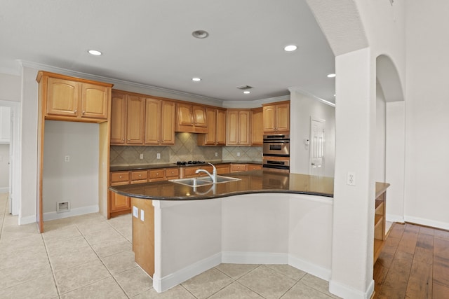 kitchen featuring light tile patterned floors, ornamental molding, a center island with sink, double oven, and sink