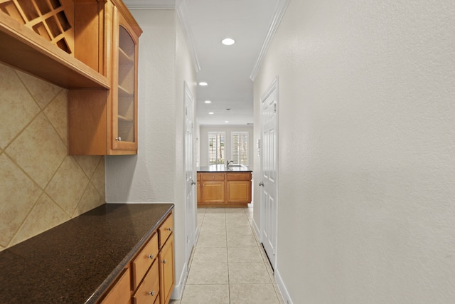 kitchen with light tile patterned flooring, dark stone counters, and ornamental molding