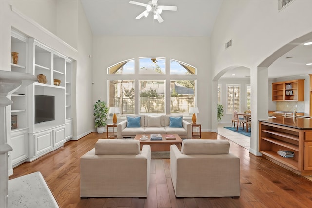 living room with light hardwood / wood-style floors, ceiling fan, and high vaulted ceiling