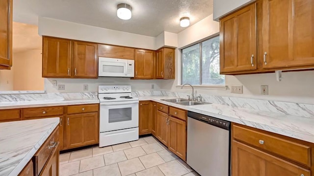 kitchen with a textured ceiling, white appliances, light tile patterned flooring, and sink