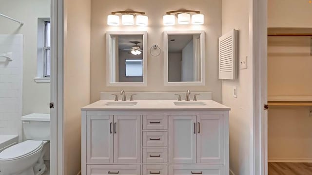 bathroom with wood-type flooring, ceiling fan, vanity, and toilet