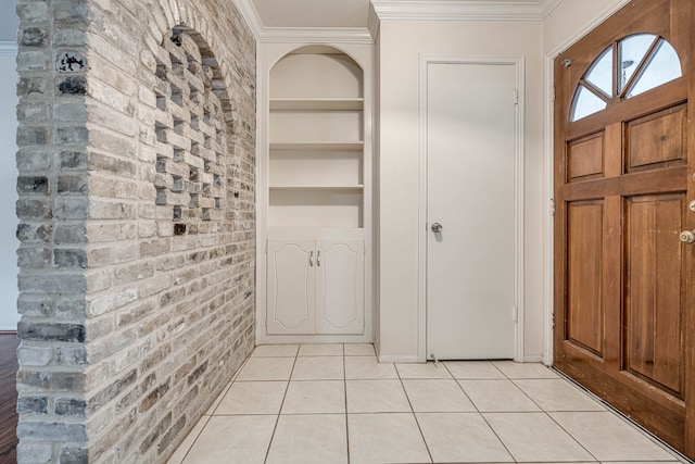 tiled foyer with brick wall and crown molding