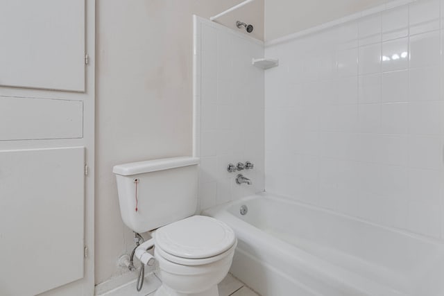 bathroom featuring tiled shower / bath combo, toilet, and tile patterned floors