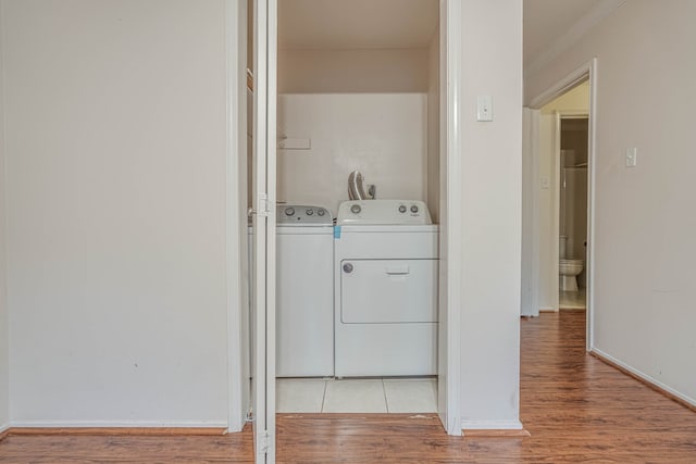 washroom with light hardwood / wood-style floors, washer and dryer, and crown molding