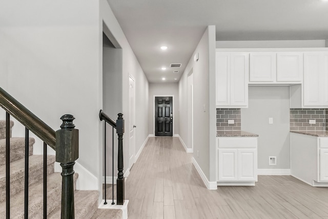 interior space featuring light wood-type flooring, white cabinetry, and tasteful backsplash