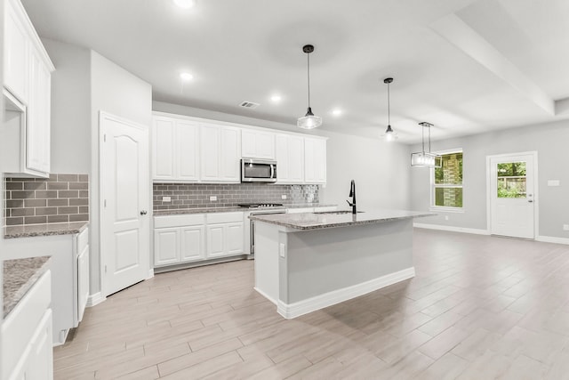 kitchen with appliances with stainless steel finishes, white cabinetry, an island with sink, decorative light fixtures, and sink