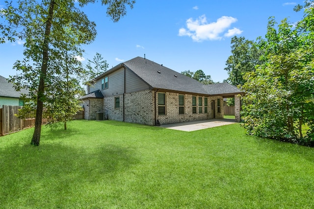 rear view of property with a lawn, central AC, and a patio area