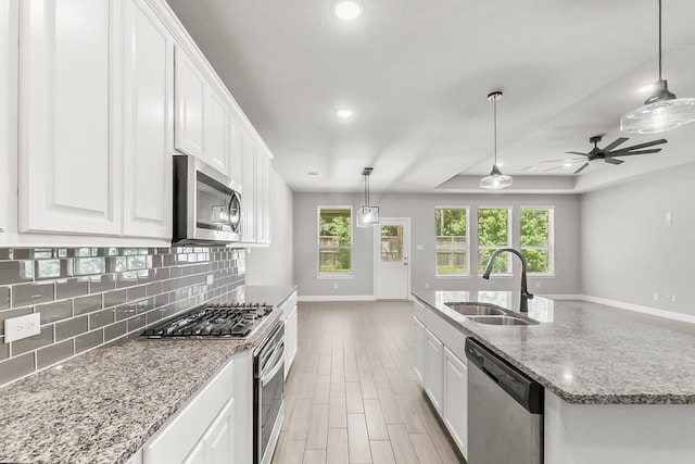 kitchen with white cabinets, stainless steel appliances, sink, and a healthy amount of sunlight