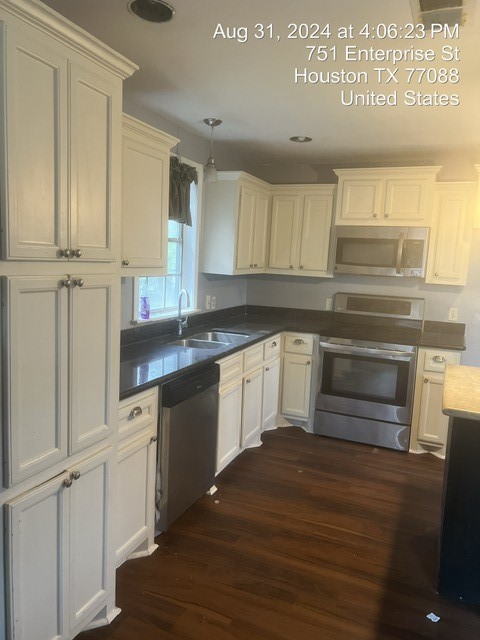 kitchen with dark wood-type flooring, stainless steel appliances, sink, and pendant lighting