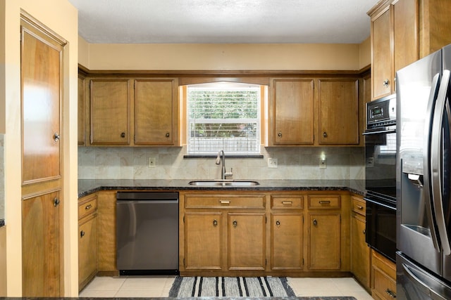 kitchen featuring dark stone counters, appliances with stainless steel finishes, light tile patterned flooring, and sink