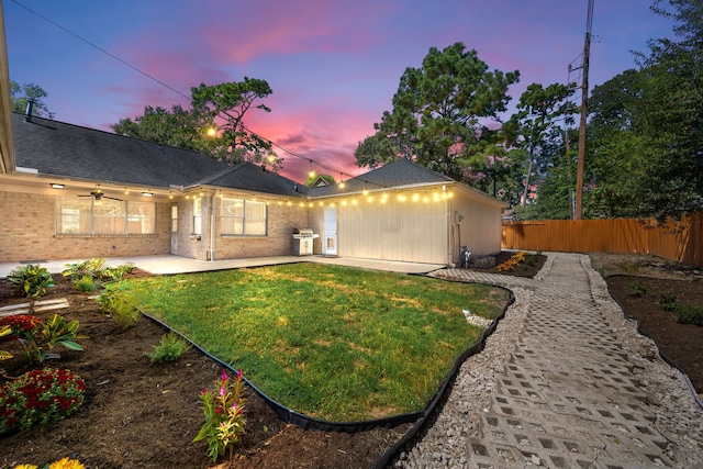 back house at dusk with a lawn and a patio