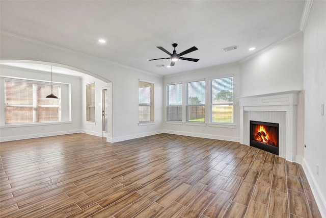 unfurnished living room featuring ceiling fan, wood-type flooring, and ornamental molding