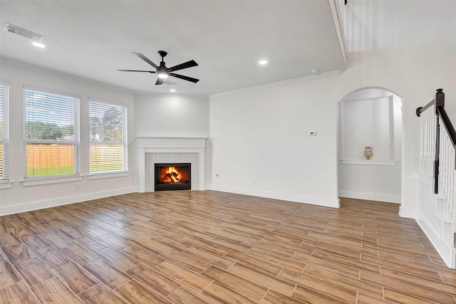 unfurnished living room featuring a fireplace, ceiling fan, light wood-type flooring, and ornamental molding