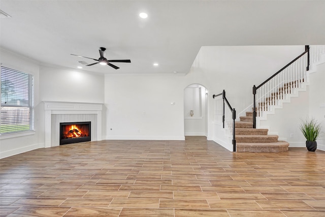 unfurnished living room featuring light hardwood / wood-style flooring, ceiling fan, and ornamental molding