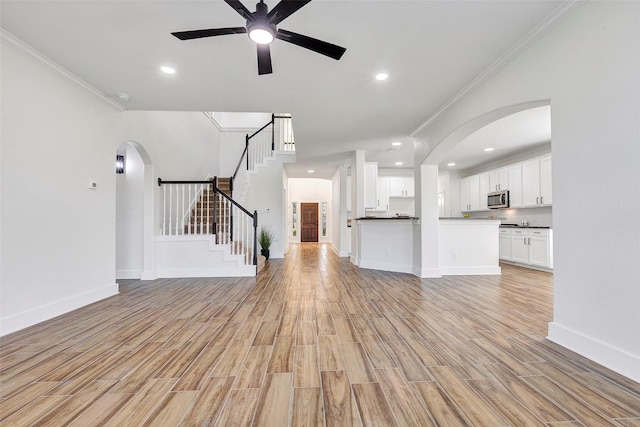 unfurnished living room with light wood-type flooring, ceiling fan, and crown molding