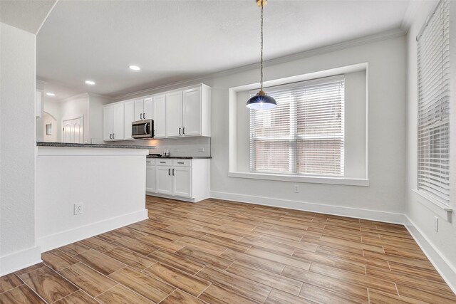 kitchen featuring decorative light fixtures, white cabinetry, and light hardwood / wood-style flooring