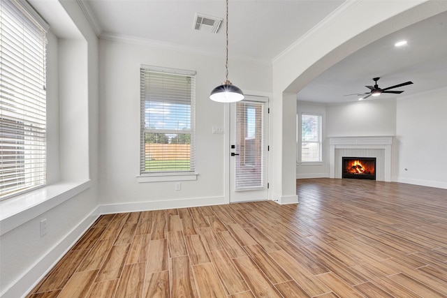 unfurnished living room featuring light hardwood / wood-style floors, a wealth of natural light, and ornamental molding