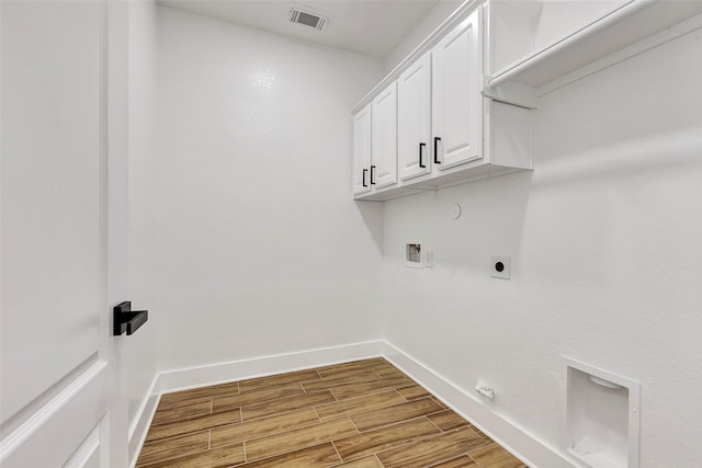 laundry room featuring electric dryer hookup, hookup for a gas dryer, cabinets, and light wood-type flooring