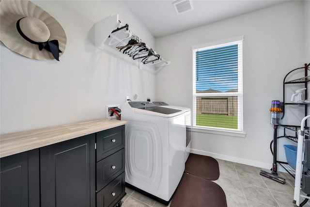 washroom with separate washer and dryer, light tile patterned floors, and cabinets