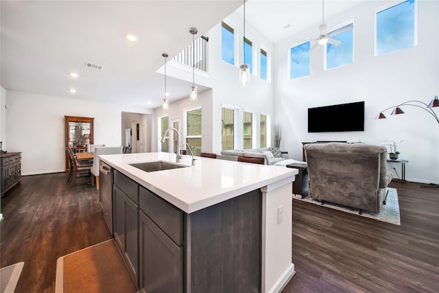 kitchen with pendant lighting, dishwasher, a center island with sink, sink, and dark hardwood / wood-style floors