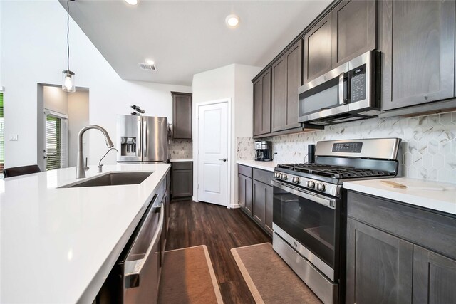 kitchen with dark brown cabinetry, sink, dark wood-type flooring, hanging light fixtures, and stainless steel appliances