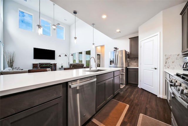 kitchen with appliances with stainless steel finishes, backsplash, dark brown cabinetry, sink, and hanging light fixtures