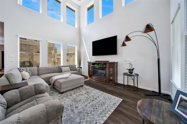 living room with a towering ceiling, a wealth of natural light, and dark wood-type flooring