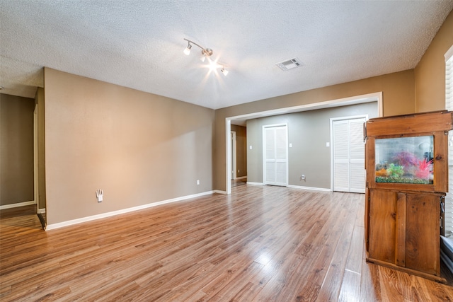 spare room with a textured ceiling and light wood-type flooring