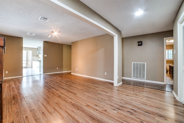 unfurnished living room featuring a textured ceiling and light hardwood / wood-style flooring