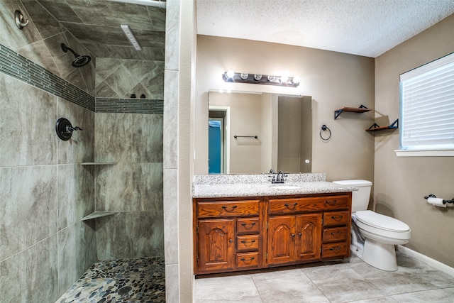 bathroom with vanity, tiled shower, a textured ceiling, and toilet