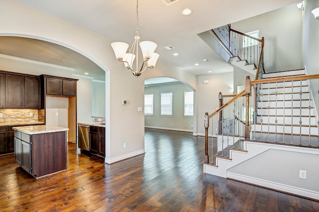 kitchen with light stone countertops, dark brown cabinetry, decorative light fixtures, a chandelier, and dark hardwood / wood-style floors