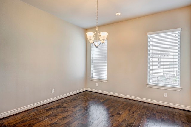 spare room with dark hardwood / wood-style flooring and a notable chandelier