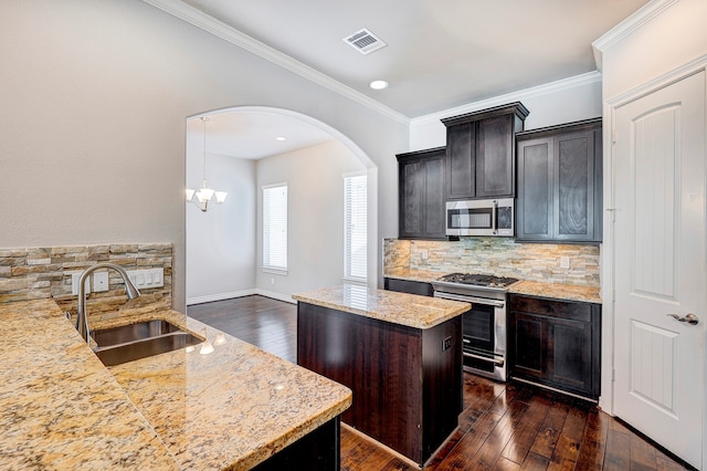 kitchen with sink, light stone countertops, decorative light fixtures, a kitchen island, and stainless steel appliances