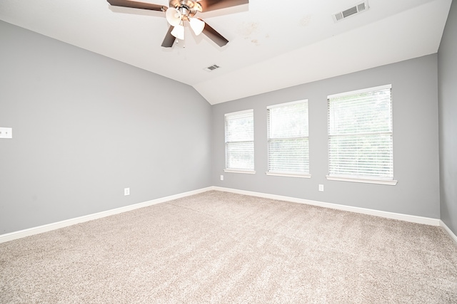 empty room featuring ceiling fan, carpet flooring, vaulted ceiling, and a healthy amount of sunlight