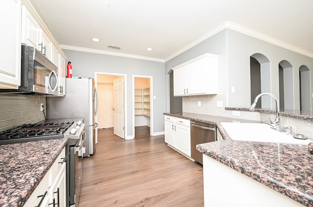 kitchen with appliances with stainless steel finishes, light hardwood / wood-style floors, and white cabinets